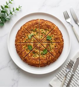 A golden corned beef omelette with a generous filling of corned beef, looking soft and appetizing, served on a skillet plate.